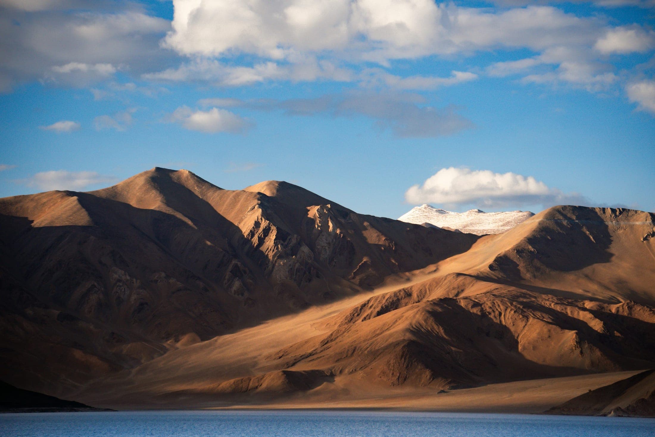Mountains rising above the still, blue water of Pangong Lake, Ladakh